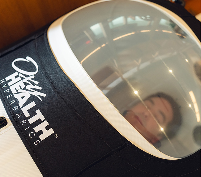 Smiling woman sitting inside a Vitaeris 320 portable hyperbaric chamber